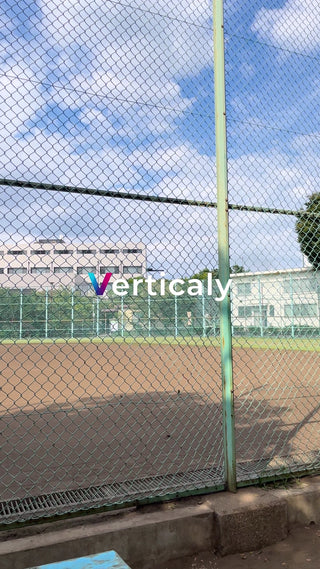 公園のフェンス越し、青空と建物