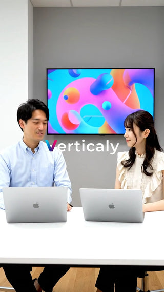 PC作業中の男女、笑顔で会話